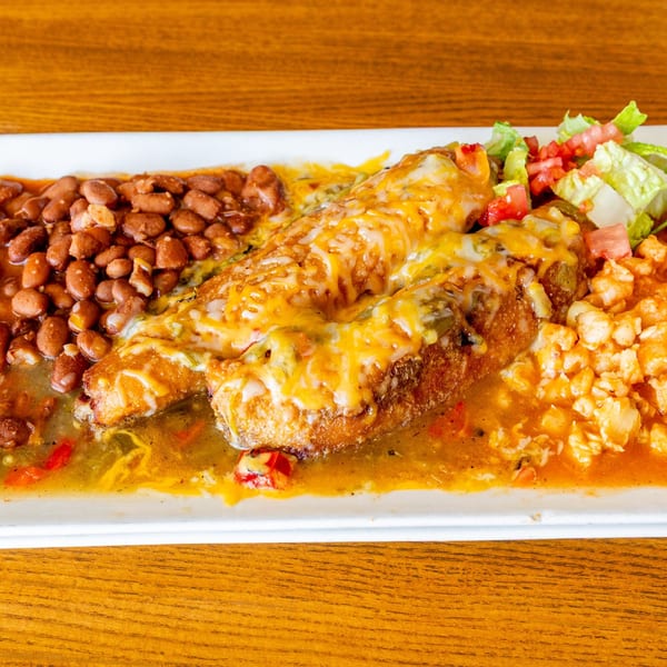 Mexican dish with cheesy chile relleno, pinto beans, rice, and a side salad on a white plate.