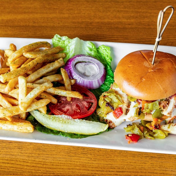A Silver Moon Cafe sandwich with fries, lettuce, tomato, onion, and a pickle on a white plate.