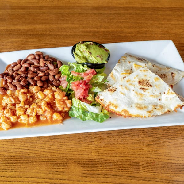 Mexican combo plate with quesadillas, beans, hominy, guacamole, and a side salad.