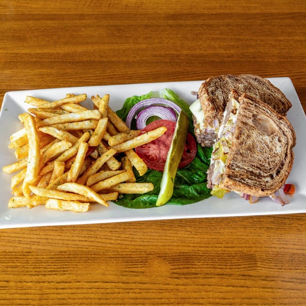 A Silver Moon Cafe sandwich with fries, lettuce, tomato, onion, and a pickle spear on a white plate.